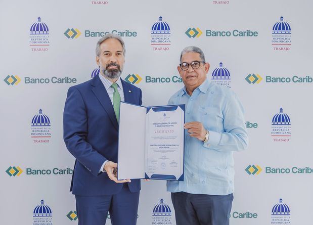 El presidente de Banco Caribe, Dennis Simó Álvarez, recibe el certificado del director general de Higiene y Seguridad Industrial del Ministerio de Trabajo, Guillermo Villamán.