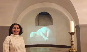 Margarita Grullón, curadora de la exposición junto al video “Agnus dei” de Jochi Muñoz en la cripta de la Iglesia Sankt Michael en la ciudad de Colonia en Alemania.

