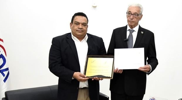 Gonell Cosme recibe placa de reconocimiento.