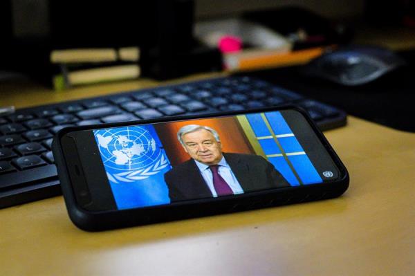 Fotografía cedida por la ONU donde aparece un teléfono móvil con la imagen de su secretario general, António Guterres, mientras habla este jueves mediante una conferencia de prensa virtual. 