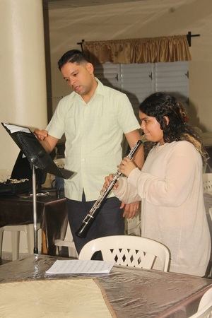 Hardy Balbino Núñez Concepción, profesor de la Orquesta Sinfónica Nacional, instruye a la joven estudiante de oboe en la técnica de respiración.