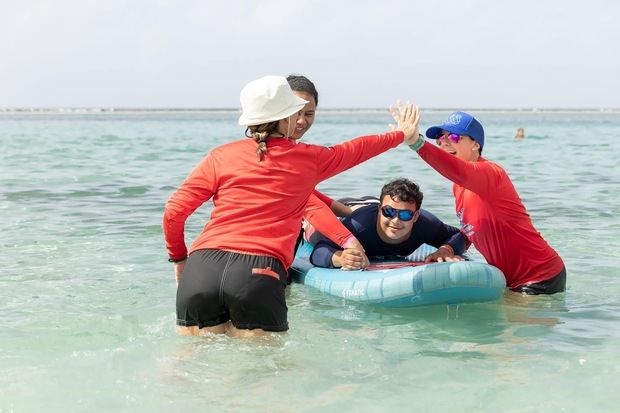 Joven disfruta la experiencia ofrecida por Surfers for Autism.