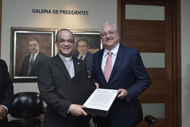 Miguel Lama, presidente del consejo directivo de la Corporación Zona Franca Santiago (CZFS) y el rector de PUCMM; presbítero doctor Alfredo de la Cruz Baldera tras la firma del acuerdo.