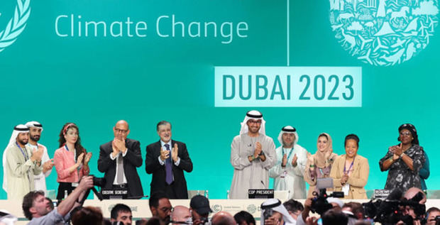 El presidente de la COP28, Sultan Jaber (centro), el representante de la ONU para el clima, Simon Stiell (cuarto de izaquierda a derecha), y otros participantes, de pie en el podio durante la clausura de la conferencia en Dubai.