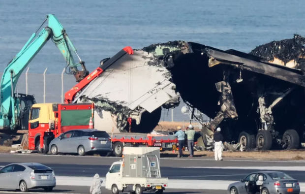 Trabajadores retiran los restos del accidente de un avión de pasajeros de Japan Airlines con un avión de la Guardia Costera nipona en el aeropuerto tokiota de Haneda, en Tokio.