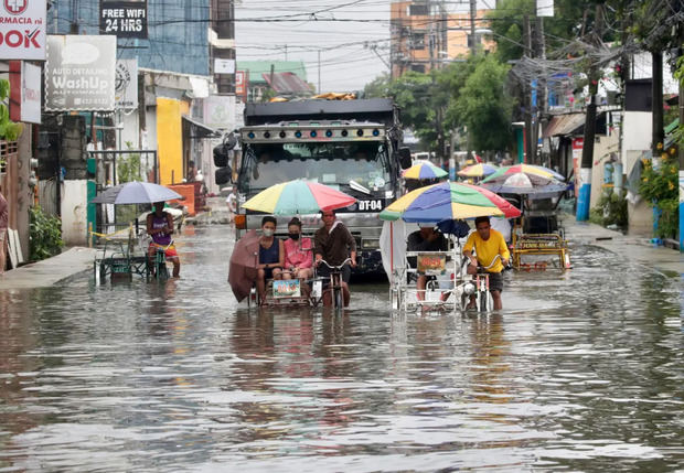 Ciudadanos filipinos fueron registrados al movilizarse en bicicletas en medio de una calle inundada, luego del paso del tifón Doksuri, en la ciudad de Valenzuela (Metro Manila, Filipinas).