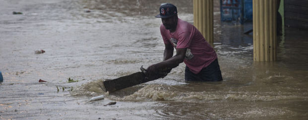 Un residente retira hoy restos en una calle inundada debido al paso de la tormenta tropical Franklin.