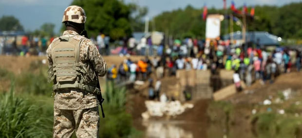 Miembros del Cuerpo Especializado en Seguridad Fronteriza Terrestre (Cesfront) de República Dominicana vigilan mientras en la orilla haitiana del río Masacre trabajadores construyen un canal de riego, desde Dajabón (República Dominicana).