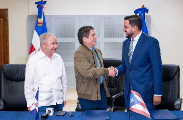 Iván Ruiz y Jorge Pagán se saludan tras la firma del acuerdo entre RTVD y WIPR TV. A la izquierda, figura Ellis Pérez.