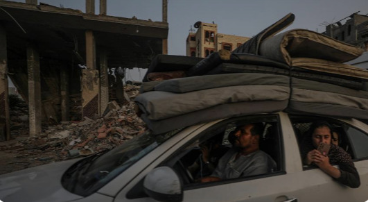 Palestinos escapan de Rafah en medio de edificios destrozados.