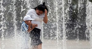 Foto de archivo de dos personas que se refrescan en una fuente de la Ciudad de México (México) para combatir las altas temperaturas.