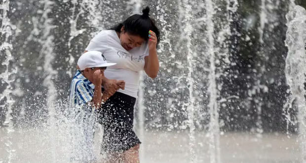 Foto de archivo de dos personas que se refrescan en una fuente de la Ciudad de México (México) para combatir las altas temperaturas.