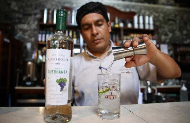Barman del antiguo bar Queirolo mientras sirve un vaso de pisco en el distrito limeño de Pueblo Libre, en Lima (Perú).