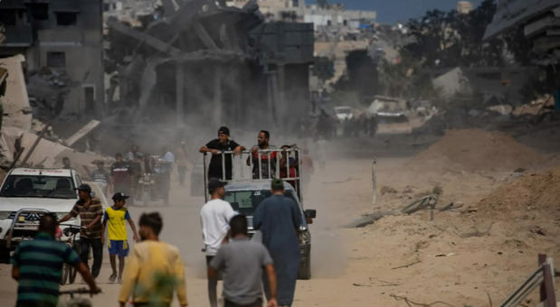 Palestinos desplazados internos se desplazan por una calle dañada mientras inspeccionan el área después de una operación militar terrestre.