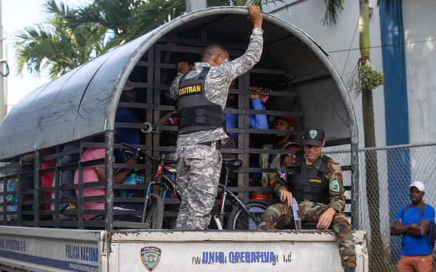 Guardias vigilan a haitianos que fueron detenidos en redadas de autoridades migratorias, durante su traslado al centro de recepción de migrantes.
