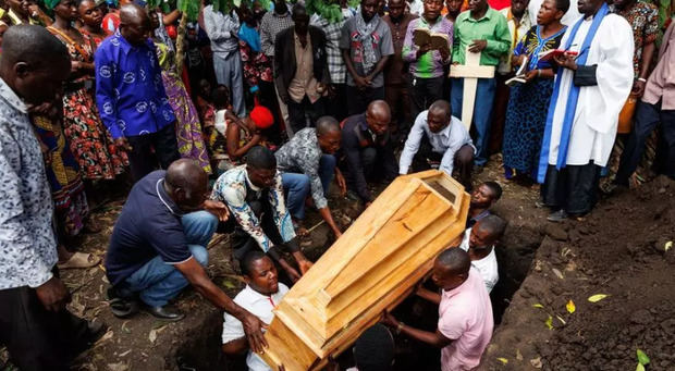 Personas bajan un ataúd a una tumba durante el funeral de una de las víctimas de un ataque en una escuela, en Mpondwe, Uganda.