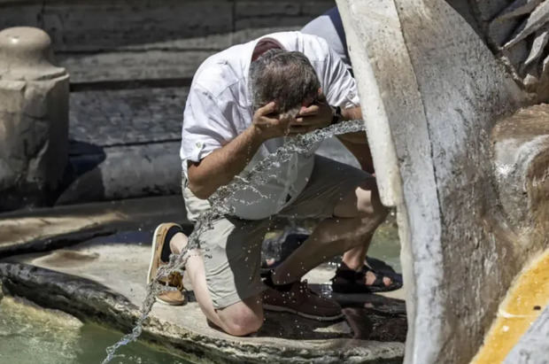 Hombre refrescándose en una fuente en Roma (Italia). 