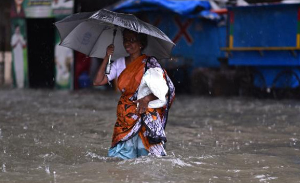 Una mujer camina por una carretera inundada durante las fuertes lluvias, ya que se espera que el ciclón Michaug toque tierra en la costa oriental de la India, en Chennai, India.