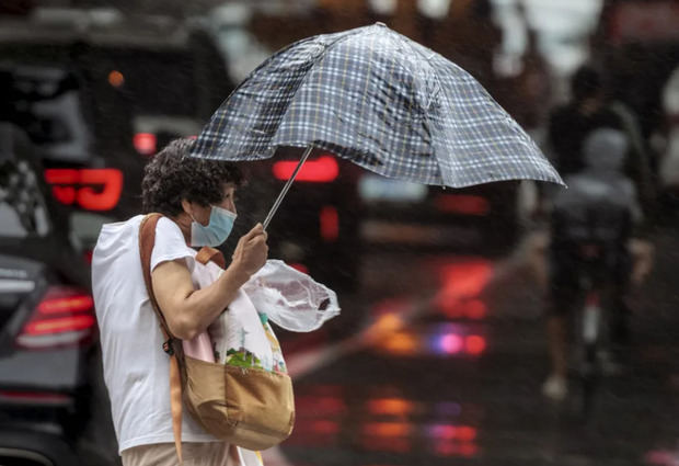 Una mujer camina por la calle durante la lluvia y el viento en medio de un tifón, en una fotografía de archivo. 