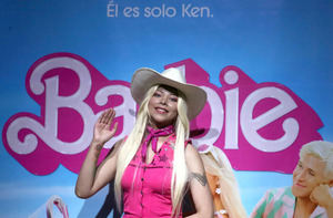 Una joven caracterizada de la muñeca Barbie saluda durante el estreno de la película Barbie.