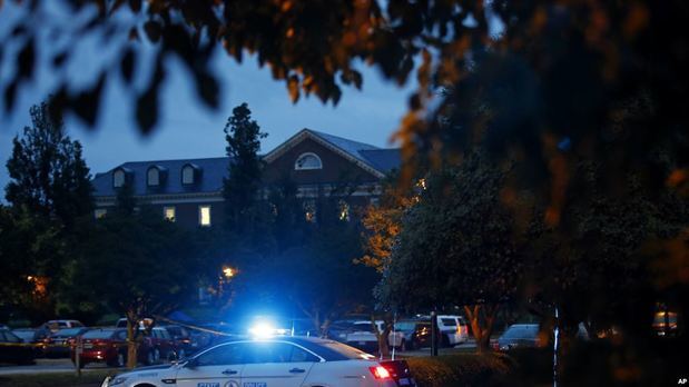 Un vehículo de la Policía del Estado de Virginia bloquea un camino hacia un edificio municipal, visto en la parte superior izquierda, que fue el escenario de un tiroteo, el sábado 1 de junio de 2019, en Virginia Beach, Virginia.