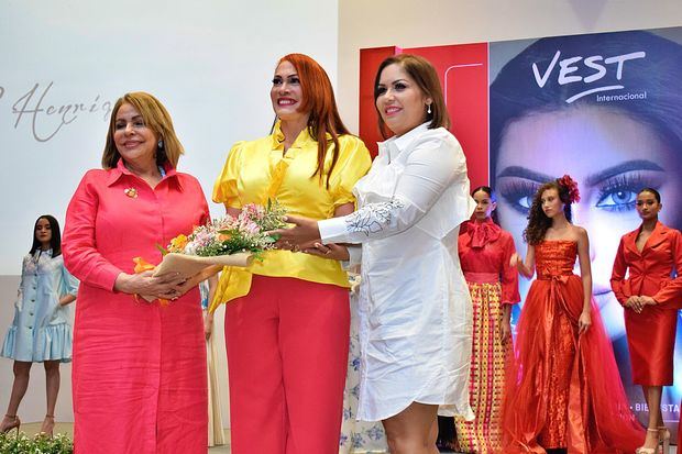 La diseñadora Marisol Henríquez recibe un ramo de flores de Luisa de Aquino y Alexandra Tabar de Vest Internacional.