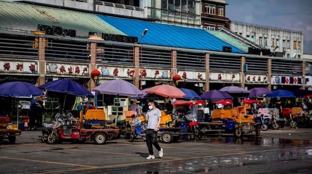 Un hombre con una mascarilla camina delante de tiendas cerradas en un mercado de mariscos en Guangzhou, provincia de Guangdong, China.