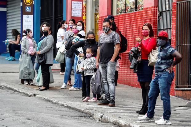 Personas con tapabocas esperan para tomar un bus de transporte público en Sao Paulo, Brasil.