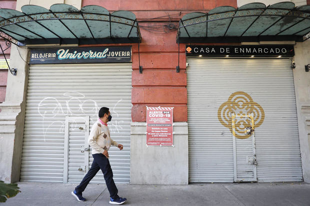 Un hombre camina frente a dos locales cerrados debido a la pandemia en Ciudad de México.