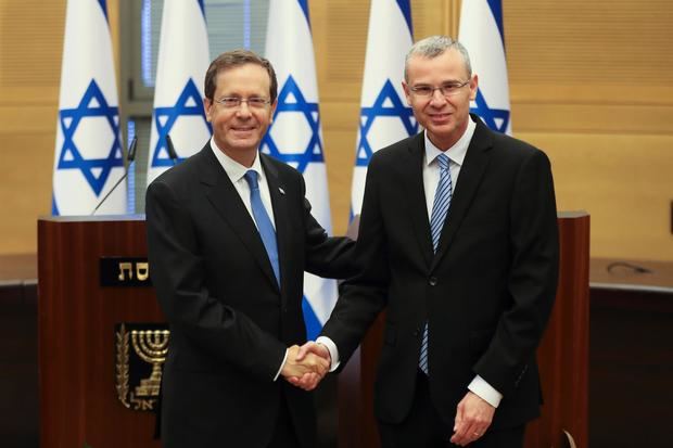 El nuevo presidente de Israel, Isaac Herzog (i) saluda al portavoz del Parlamento Yariv Levin, antes de la sesión especial de la Knesset en la que ha sido elegido.