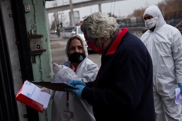 Trabajadores municipales de la comuna de San Ramón reparten cajas con alimentos básicos a familias vulnerables afectadas por las consecuencias de la cuarentena obligatoria decretada para detener el avance de la COVID-19, este jueves, en Santiago, Chile. 