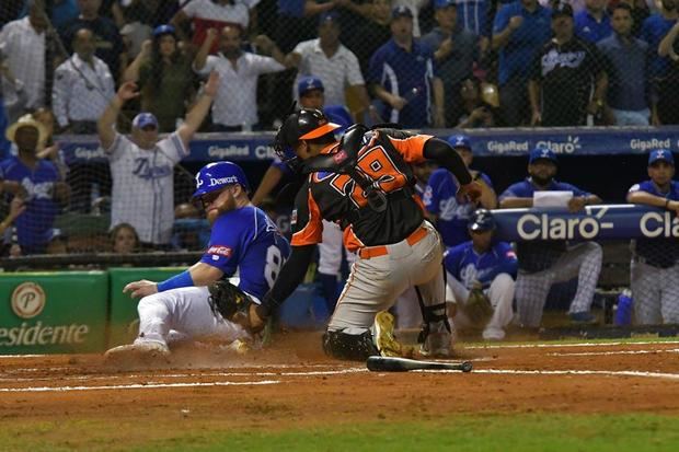 El refuerzo norteamericano de los Tigres de Licey Eric Filia, es puesto fuera por el receptor de los Toros del Este Christian Bethancourt este domingo, durante el sexto partido de la serie final del Torneo de Béisbol Invernal, en el estadio Quisqueya Juan Marichal.