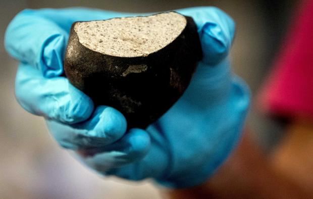 Un científico muestra un meteorito tipo condritas.