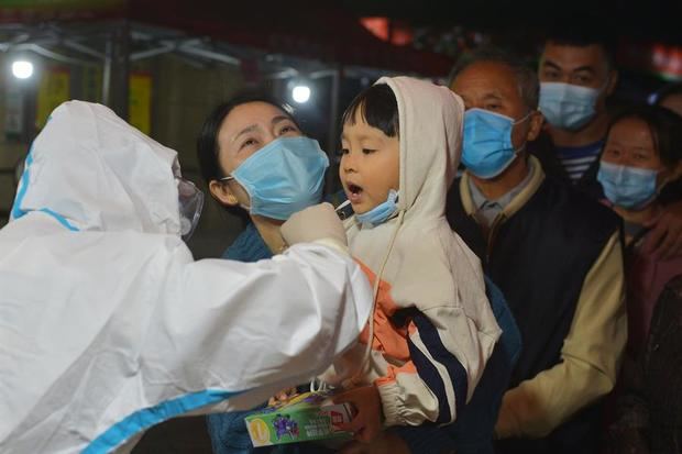 Un trabajador médico toma una muestra de hisopo de un niño residente para la nueva prueba de coronavirus en un bloque residencial en la ciudad de Qingdao, provincia de Shandong, China.