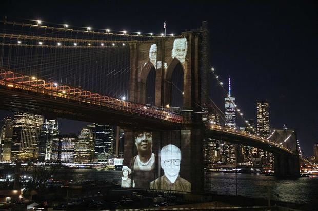 Imágenes de personas que murieron por complicaciones relacionadas con la enfermedad covid-19 fueron proyectadas este domingo sobre el Puente de Brooklyn, durante una ceremonia conmemorativa para recordar a las más de 30.000 víctimas de la pandemia en la 'gran manzana', en el distrito de Brooklyn, NY, EE.UU.
