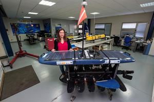 La ingeniera de Robótica de la Plataforma Oceánica de Canarias (Plocán), Tania Morales, muestra el 'wave glider' (un robot que navega por la superficie impulsado por la energía de las olas) que ha recorrido en los dos últimos meses 2.000 kilómetros entre los archipiélagos de Azores, Madeira y Canarias recopilando datos sobre el océano, los cetáceos y el ruido del tráfico marítimo. Detrás de ella, un planeador submarino (en amarillo) y un navegador de superficie a vela (azul).