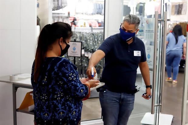 Un trabajador rocía desinfectante a una clienta durante su ingreso a una tienda en el centro comercial Plaza Las Américas, en San Juan, Puerto Rico.