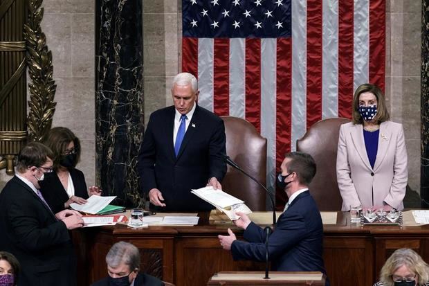 El vicepresidente de EEUU, Mike Pence, da lectura en el Capitolio al acta que confirma al demócrata Joe Biden como el próximo presidente del país, junto a la presidenta de la Cámara de Representantes, Nancy Pelosi.