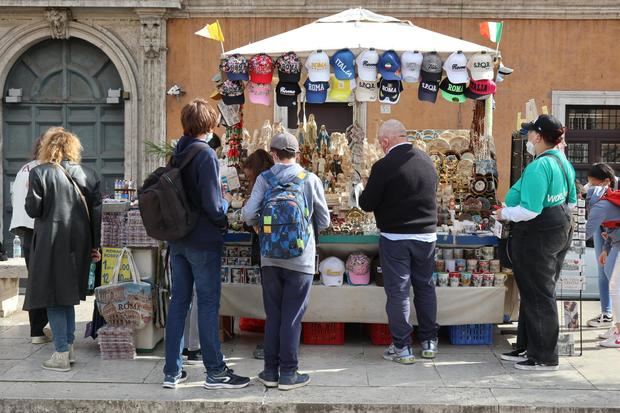 Un grupo de turistas compran recuerdos en uno de los típicos puestos de los aledaños del Vaticano.