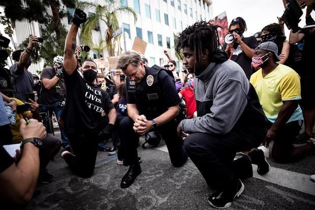 El comandante del LAPD, Cory Palka (C), se arrodilla junto a los manifestantes junto a la casa del alcalde de Los Ángeles, Eric Garcetti, mientras miles de manifestantes salieron a la calle para manifestarse tras la muerte de George Floyd, en Los Ángeles, California, EE. UU.