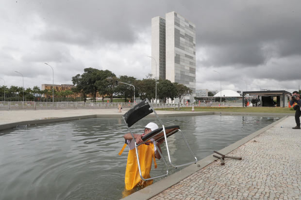 Un hombre saca hoy una silla de uno de los cuerpos de agua que rodean el Palacio de Planalto, en Brasilia, después de que manifestantes bolsonaristas tomaran en la víspera la Plaza de los Tres Poderes para invadir los edificios gubernamentales.