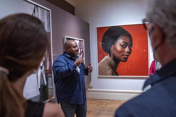 Kwame S. Brathwaite, habla a los asistentes mientras expone sobre una de las obras de su padre, el fotógrafo Kwamw Brathwaite, este 18 de agosto de 2022 durante la muestra fotográfica 'Black is beautiful', en el museo New York Historical Society, en New York, Estados Unidos.