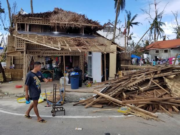 Una foto distribuida por la Oficina del Vicepresidente de Filipinas (OVP) muestra a un aldeano caminando junto a una casa dañada y los escombros a lo largo de una carretera en la devastada ciudad de General Luna, isla de Siargao, Filipinas, el 19 de diciembre de 2021.