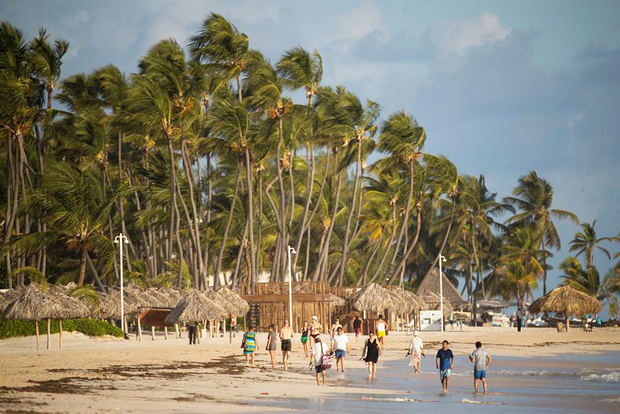 Turistas caminan por playa Bávaro, uno de los principales destinos turísticos del Caribe, en Punta Cana, República Dominicana.