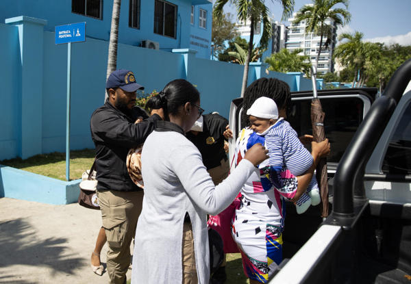 Dos mujeres haitianas y sus bebés al ser conducidas este lunes, 21 de abril, al interior de un vehículo de migración, a las afueras del Hospital Maternidad Nuestra Señora de la Altagracia, en Santo Domingo (República Dominicana), luego de que autoridades dominicanas empezaran a exigir documentación a los migrantes haitianos. 