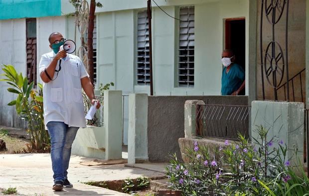 Un trabajador de la salud pública en Cuba da orientaciones a pobladores durante la labor de 'pesca' de pacientes en el poblado de Zaragoza este martes, en el municipio de San José de las Lajas, provincia de Mayabeque, Cuba. 