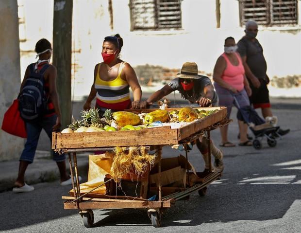 Un hombre protegido con mascarilla empuja una carretilla con productos agrícolas a la venta en La Habana (Cuba).