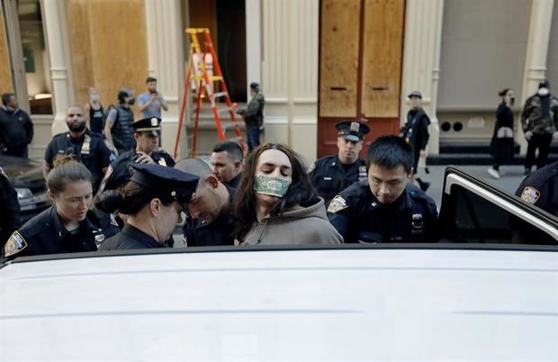 La policía arresta a un hombre con un billete de un dólar en la boca en el barrio neoyorquino de Soho después de las últimas noches saqueando disturbios como parte de la respuesta de los manifestantes a la muerte de George Floyd, en Nueva York, Nueva York, Estados Unidos.