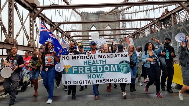 Decenas de activistas y personas antivacunas caminan durante una marcha antivacunas hoy, en el puente de Brooklyn, Nueva York, EE.UU.