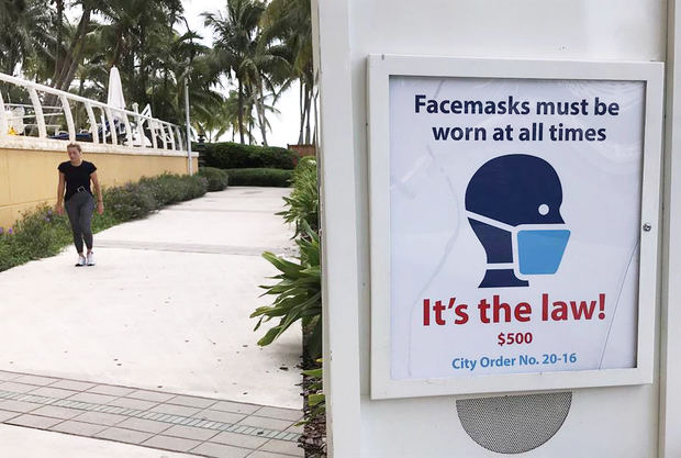 Una persona camina junto a un cartel que advierte ponerse mascarilla, el 6 de julio de 2020, en Florida, Estados Unidos.